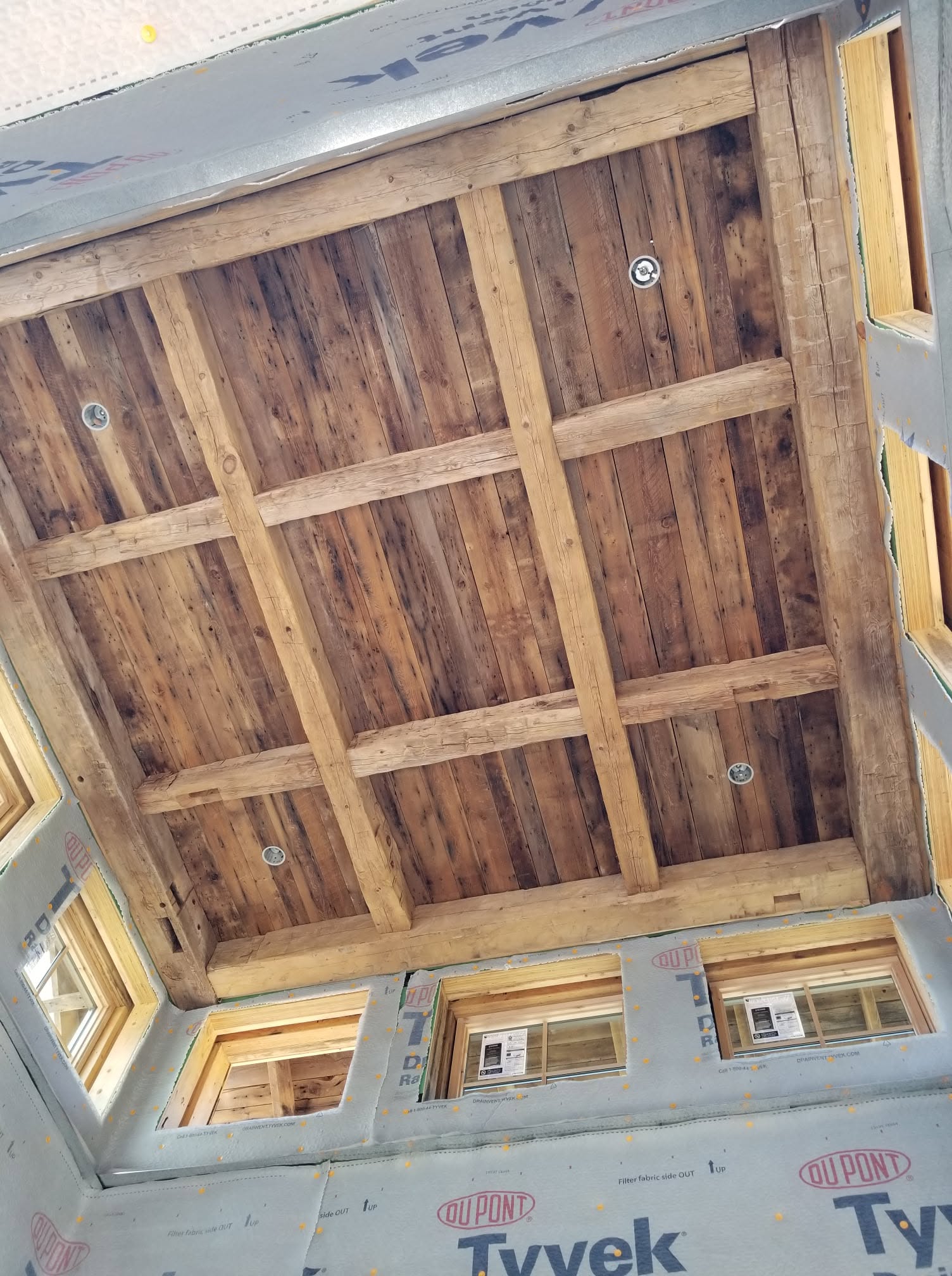 Reclaimed wood ceiling with a grid of heavy timber beams and recessed lights