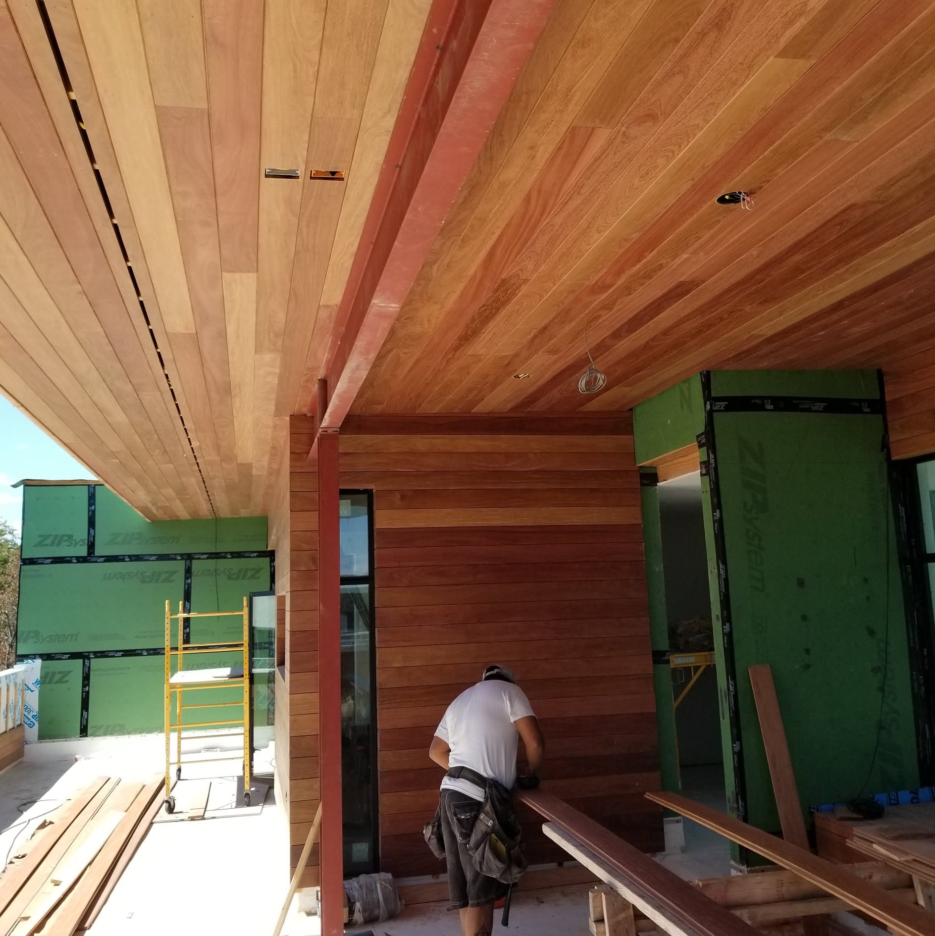 Craftsperson installing cedar boards beneath a covered patio